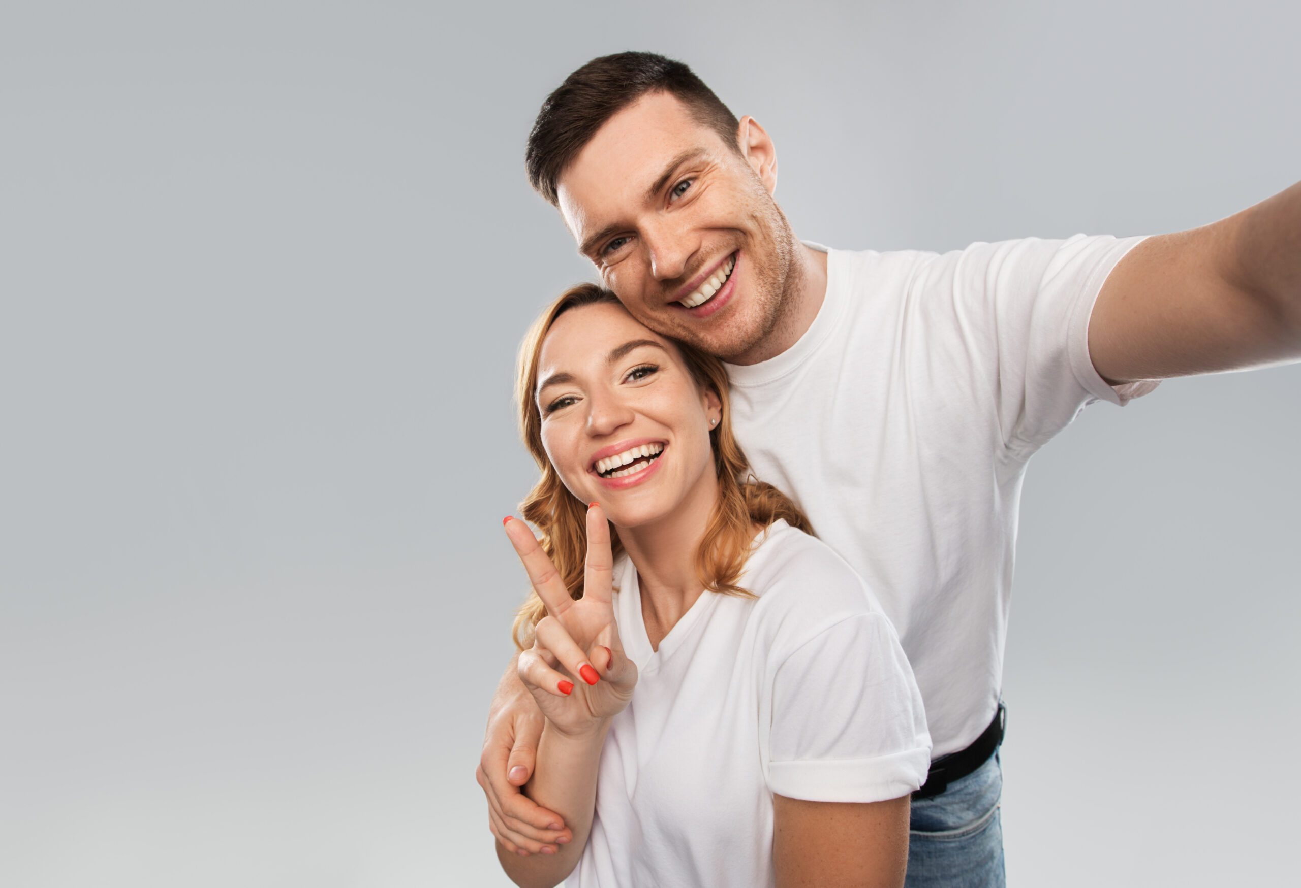 happy couple in white t-shirts taking selfie